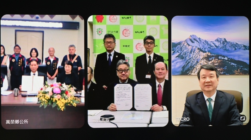 在駐日代表李逸洋(右邊螢幕)見證下，花蓮縣萬榮鄉長(左邊螢幕前排右2)與北海道平取町長(中間螢幕前排右2)簽署友好交流協定。