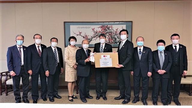 洪勝信会長(左5)が防疫防護服を大阪市政策企画室吉村室長(右5)に寄贈。李世丙処長(右4)、辻純子会長(左4)が出席。