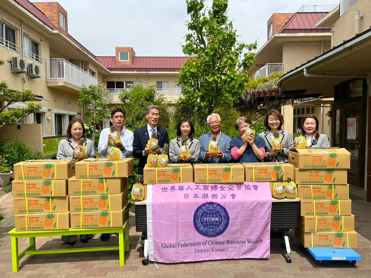 向処長(左から3番目)立ち会いのもと、劉会長(左から4番目)が寄贈した台湾パイナップルを代表して受け取る永野理事長(右から4番目)